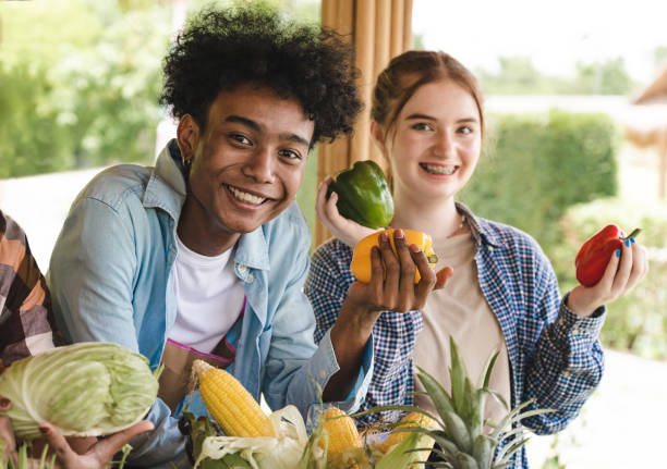 Happy teenagers holding vegetables.