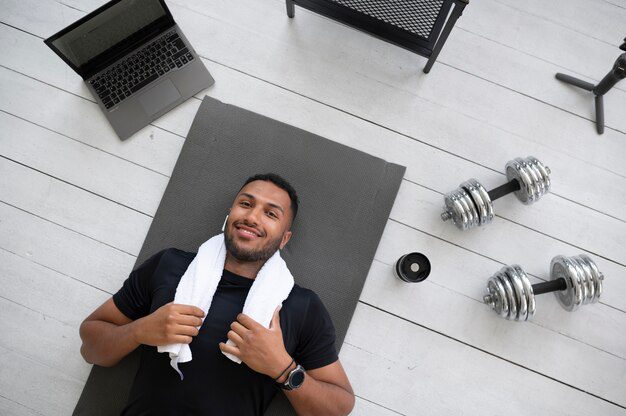 A man happy with starting a workout routine. He is lying on his back looking satisfied.