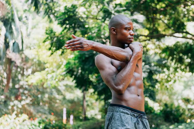 A man shirtless, stretching in the woods. A depiction that he has been able to build strong bones