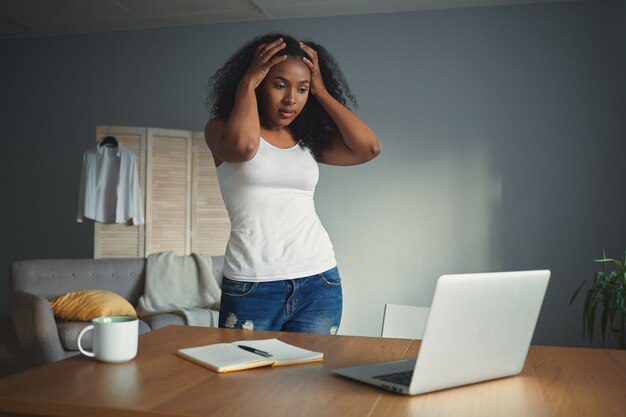 A lady in front of her workspace with her hands on her head  to show stress and overwhelm in the digital age. 