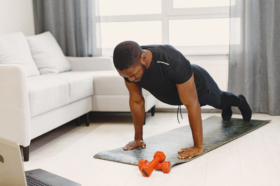 A man in plank position with dumbbells, to show home workouts or gym workouts